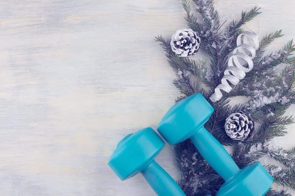 Dumbbells against the background of a spruce branch with holiday decorations