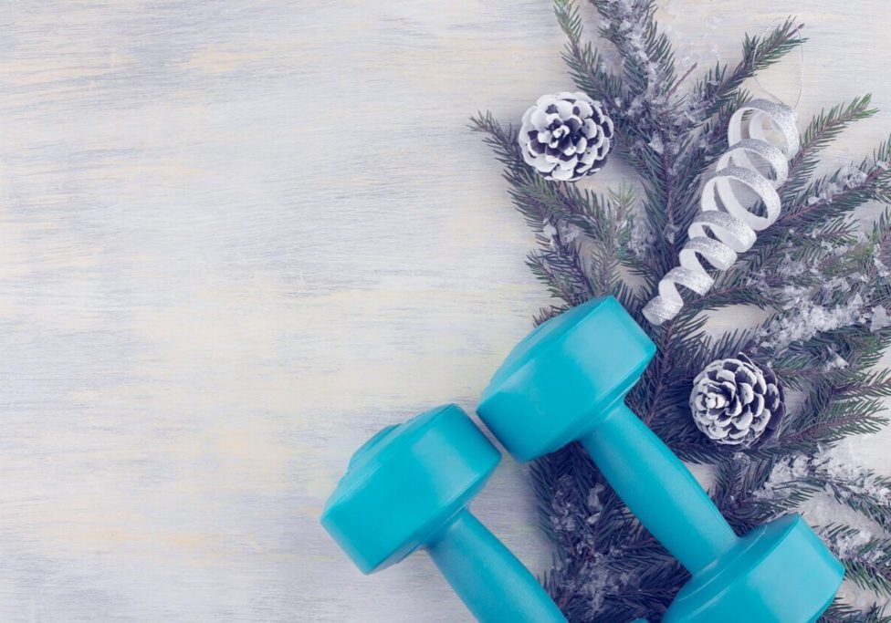 Dumbbells against the background of a spruce branch with holiday decorations